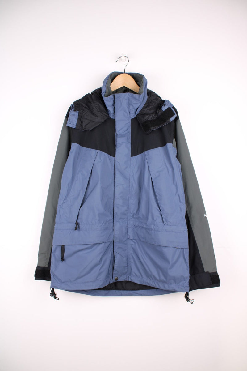 The North Face Hydroseal blue and grey zip through waterproof jacket. Features multiple pockets, foldaway hood and embroidered logo on the sleeve