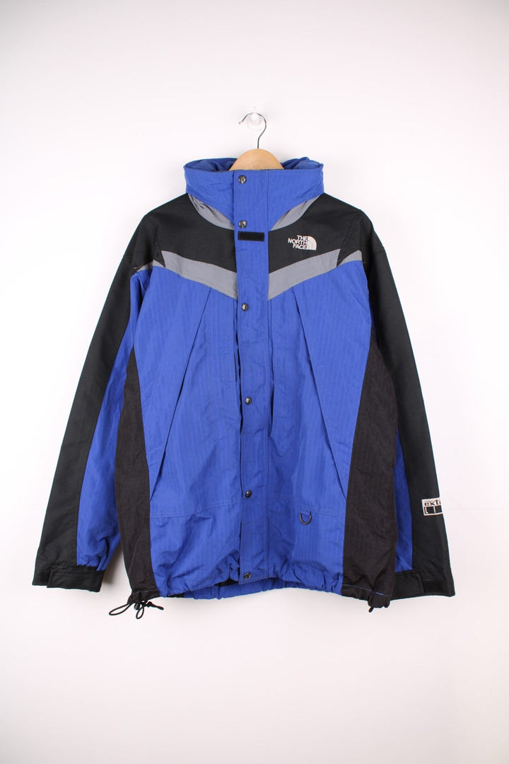 The North Face Extreme Light jacket in blue and black. Features embroidered logos, multiple pockets and foldaway hood 