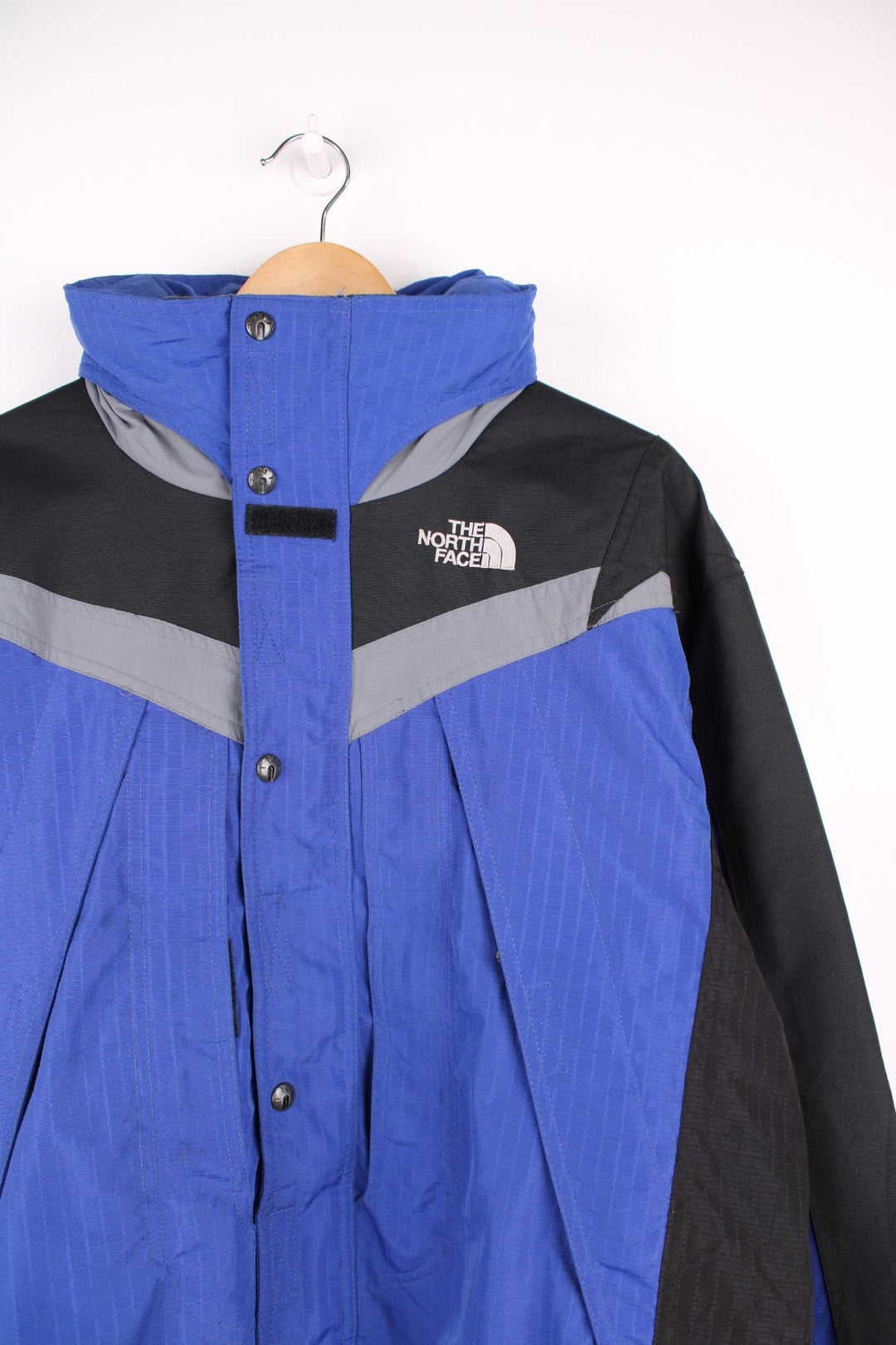 The North Face Extreme Light jacket in blue and black. Features embroidered logos, multiple pockets and foldaway hood 