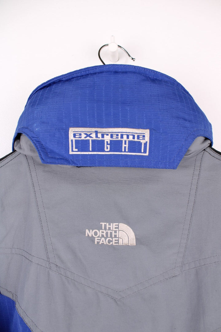 The North Face Extreme Light jacket in blue and black. Features embroidered logos, multiple pockets and foldaway hood 