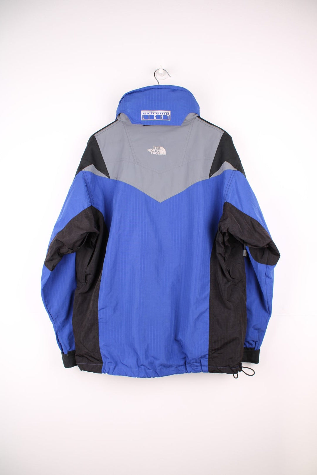 The North Face Extreme Light jacket in blue and black. Features embroidered logos, multiple pockets and foldaway hood 