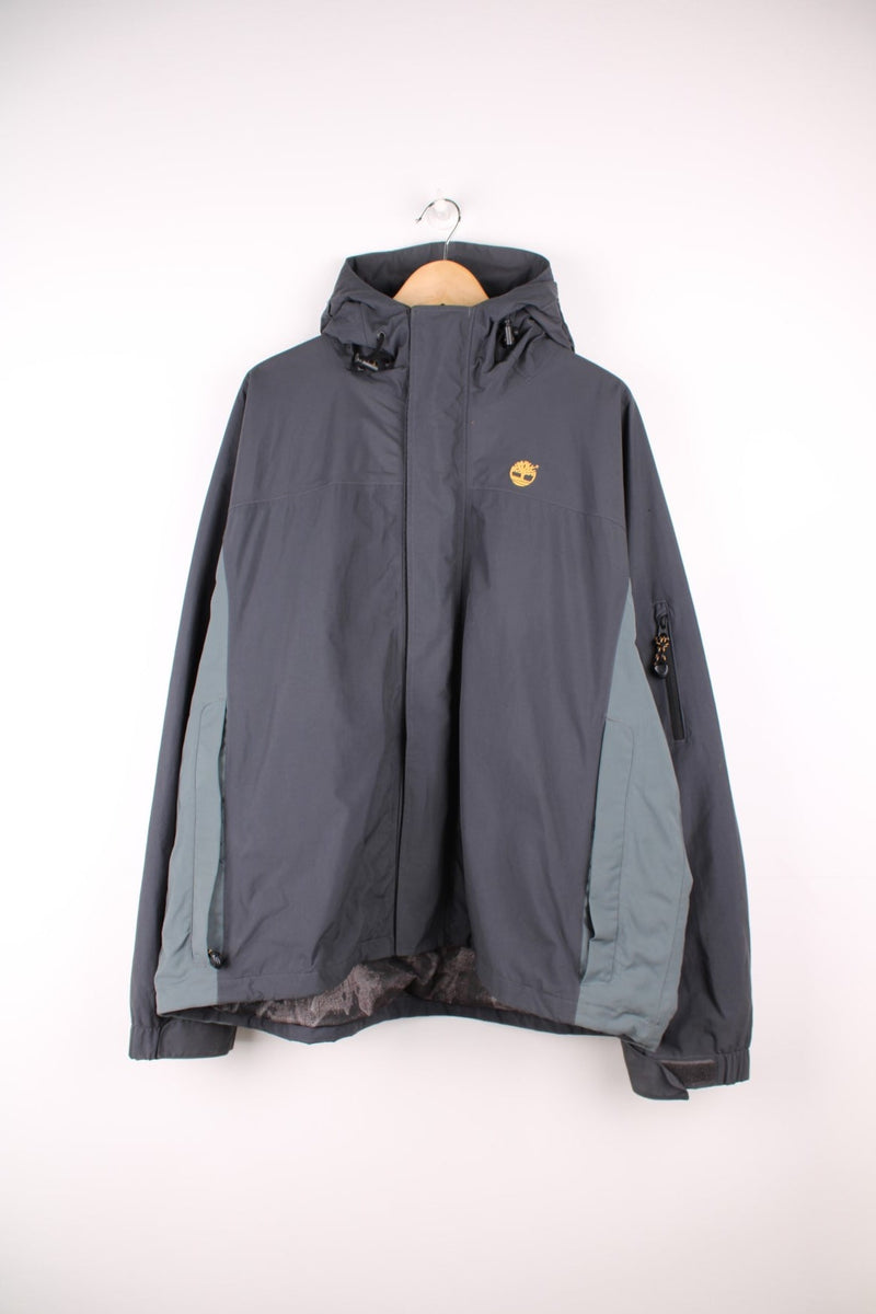 Grey tone Timberland outdoor jacket with hood. Features zip up pockets elasticated hem and embroidered logo on the chest