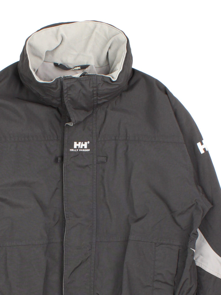 Helly Hansen Jacket in a black colourway. Multiple zip pockets and drawstring hem, and has the logo embroidered across the back and small logo on front and sleeve.