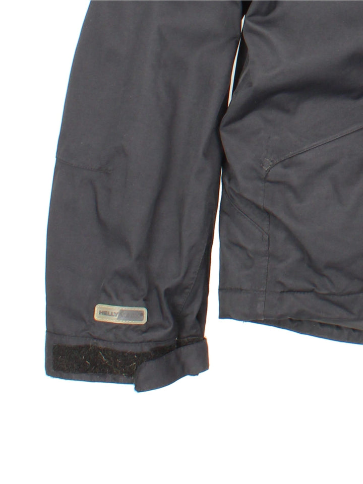 Helly Hansen Jacket in a black colourway. Multiple pockets on front, sides and inside. Drawstring hood and has the small logo embroidered on the sleeve and on the front.