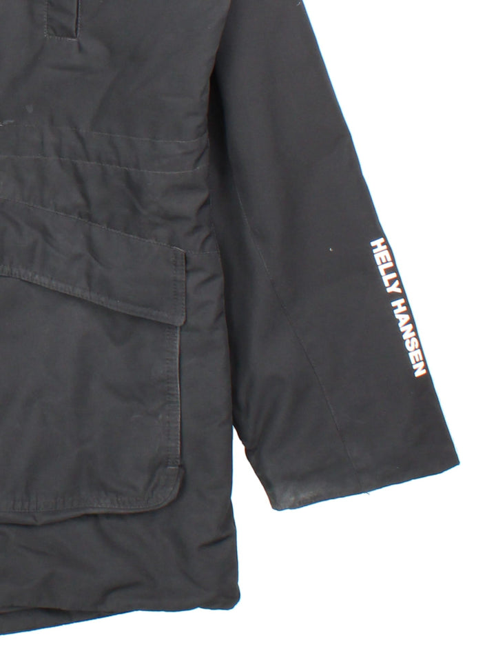 Helly Hansen Parka Coat in a black colourway. Multiple pockets on front and has a faux fur parka hood and the logo on the front.