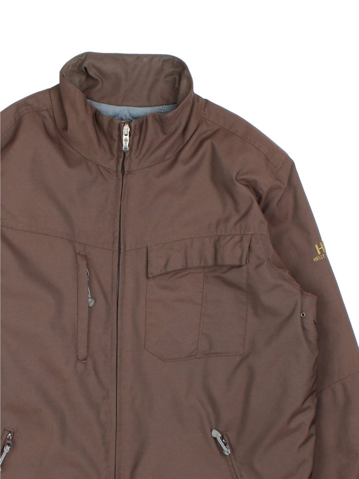 Helly Hansen Jacket in a brown colourway. Has multiple pockets, full zip closure and insulated with a quilted lining. Has the logo on the left sleeve.