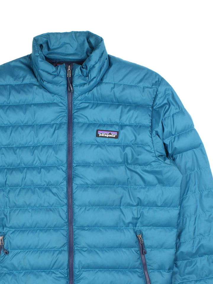 Vintage Patagonia Puffer Jacket in a blue colourway with contrast lining. Zip fastening/pockets, embroided patch logo on the front.