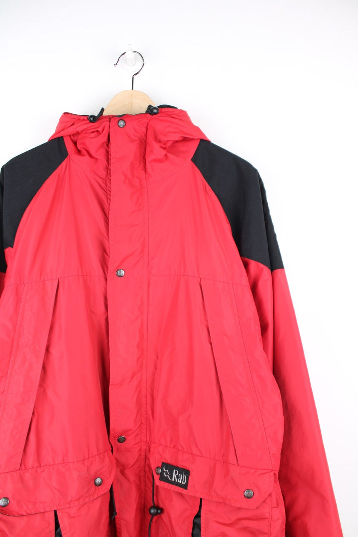 Vintage Rab red and black hooded rain jacket with multiple pockets and embroidered logo.