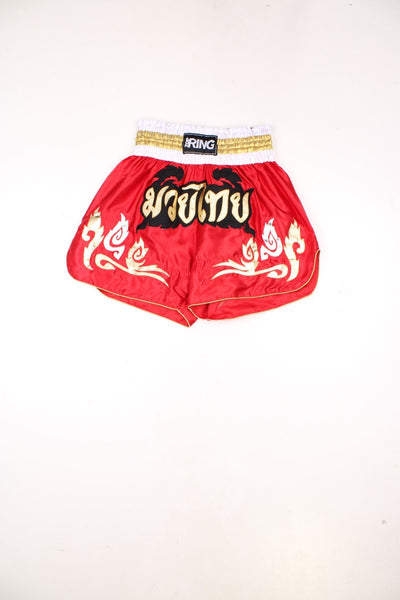 Red Thai boxing shorts with silver, gold and black embroidered embellishments.