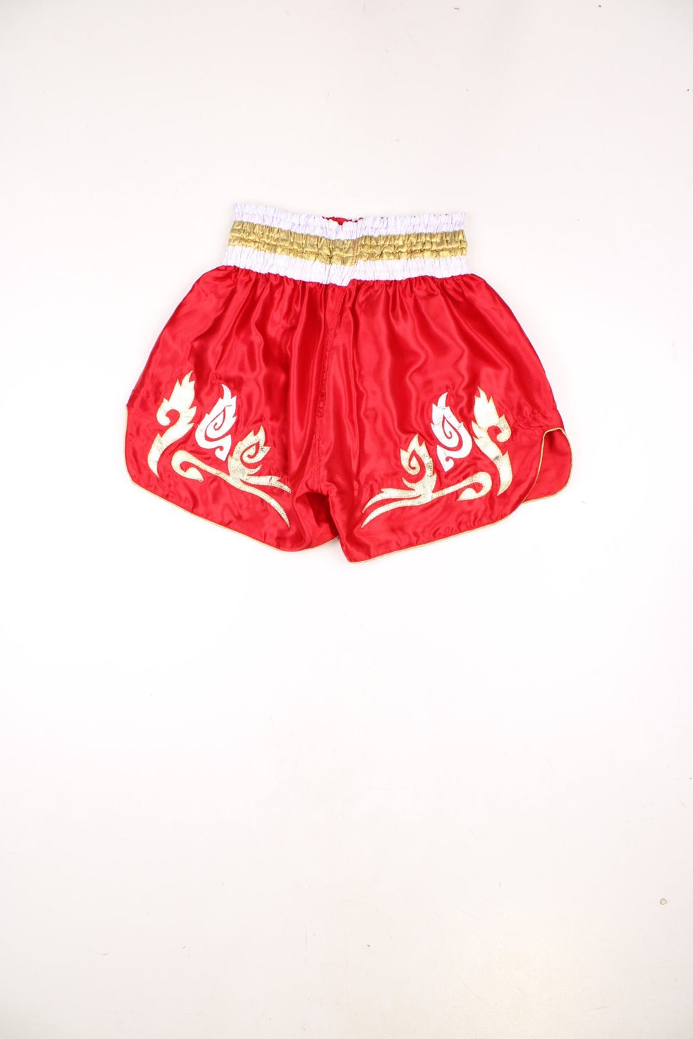 Red Thai boxing shorts with silver, gold and black embroidered embellishments.