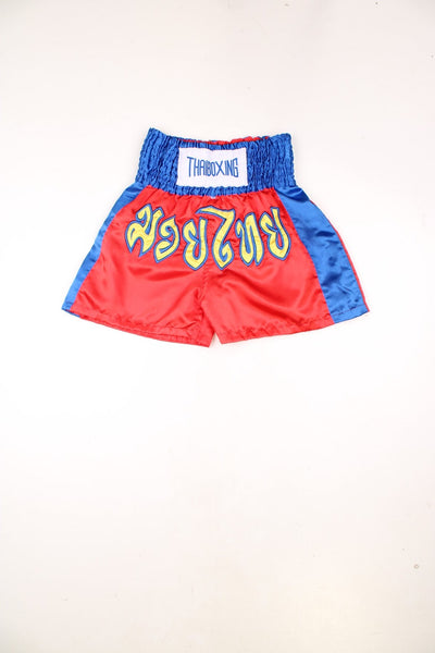 Red and blue Thai boxing shorts with embroidered yellow lettering.