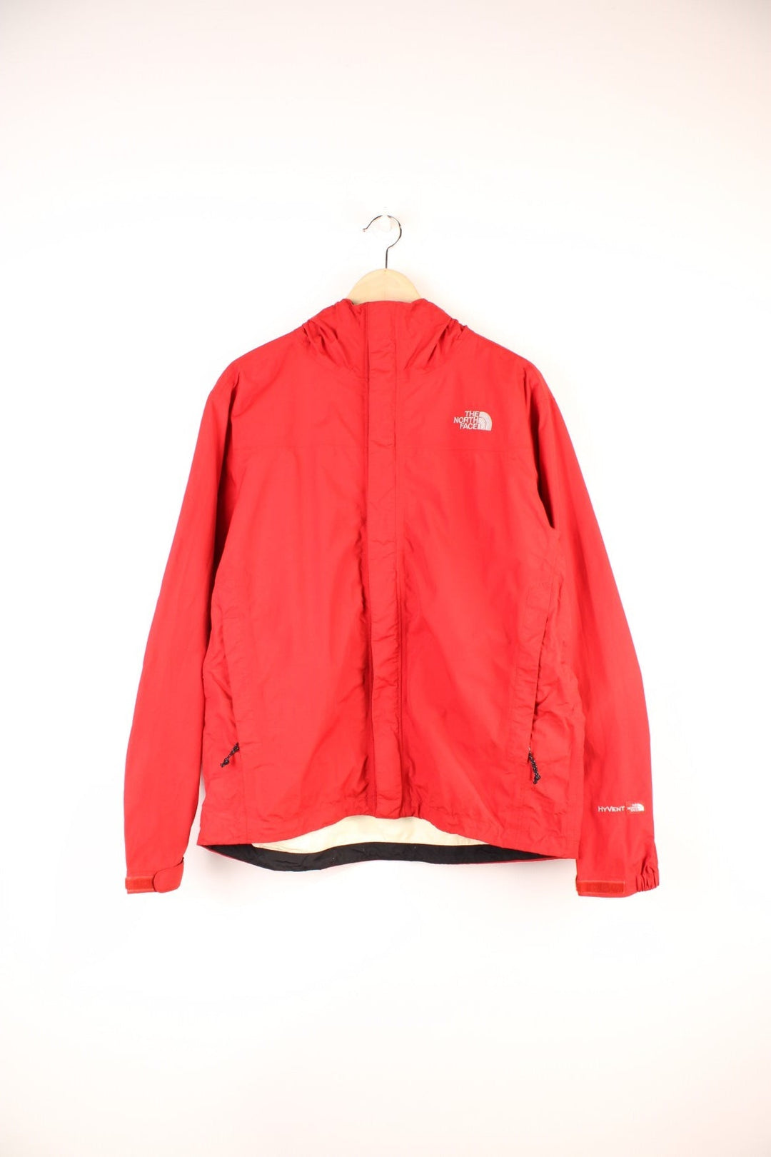 The North Face Hyvent Jacket in a red colourway, zip up with side pockets, hooded, and has the logo embroidered on the front and back. 