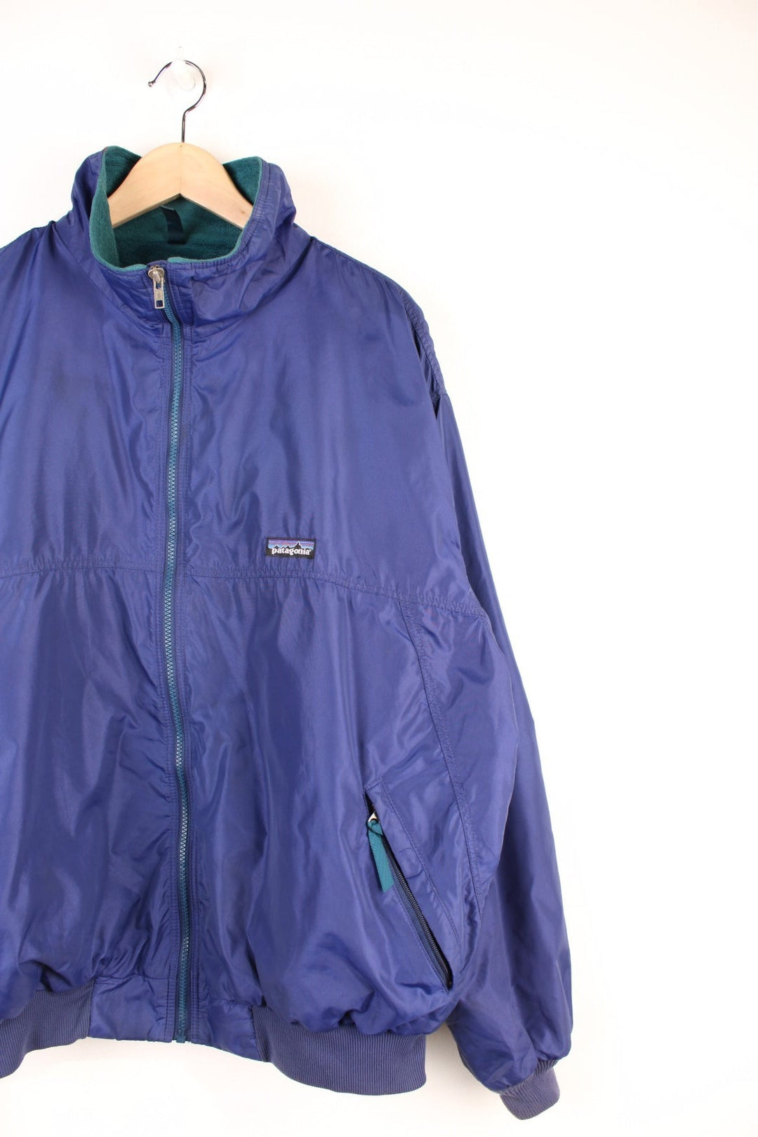 Patagonia Synchilla Jacket in a blue colourway with a green fleece lining, zip up with side pockets, and has the logo embroidered on the front. 