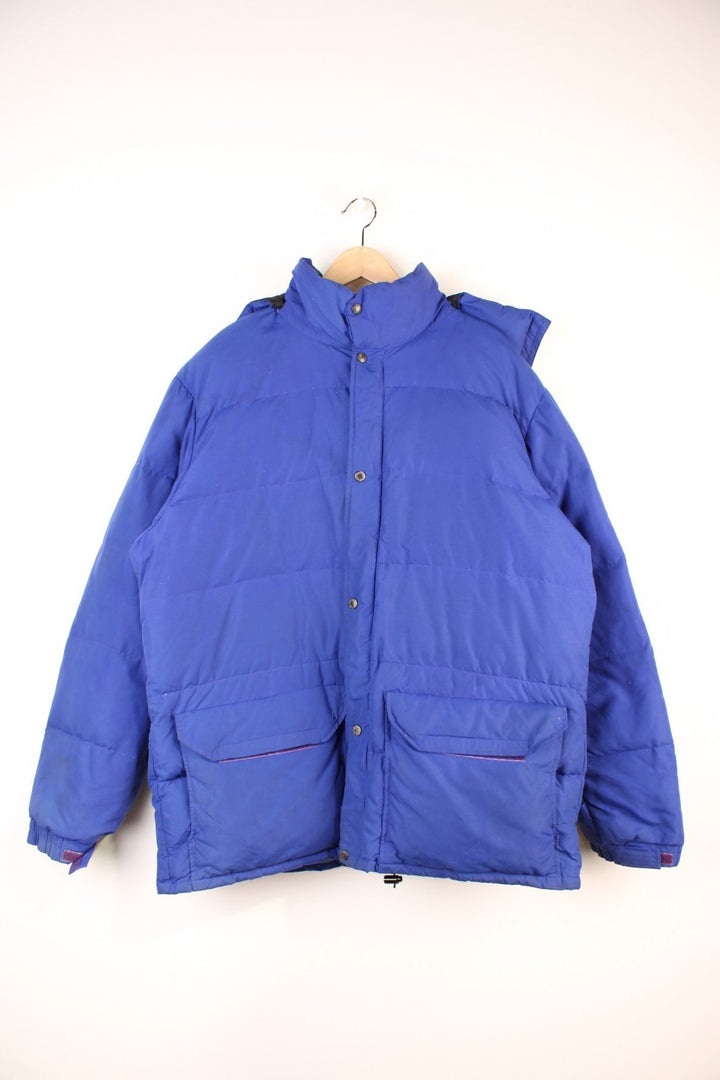 Vintage 90's The North Face Baltoro Down Puffer Coat in a blue colourway, zip up with side pockets, insulated, has a detachable hood and the logo embroidered on the left sleeve. 