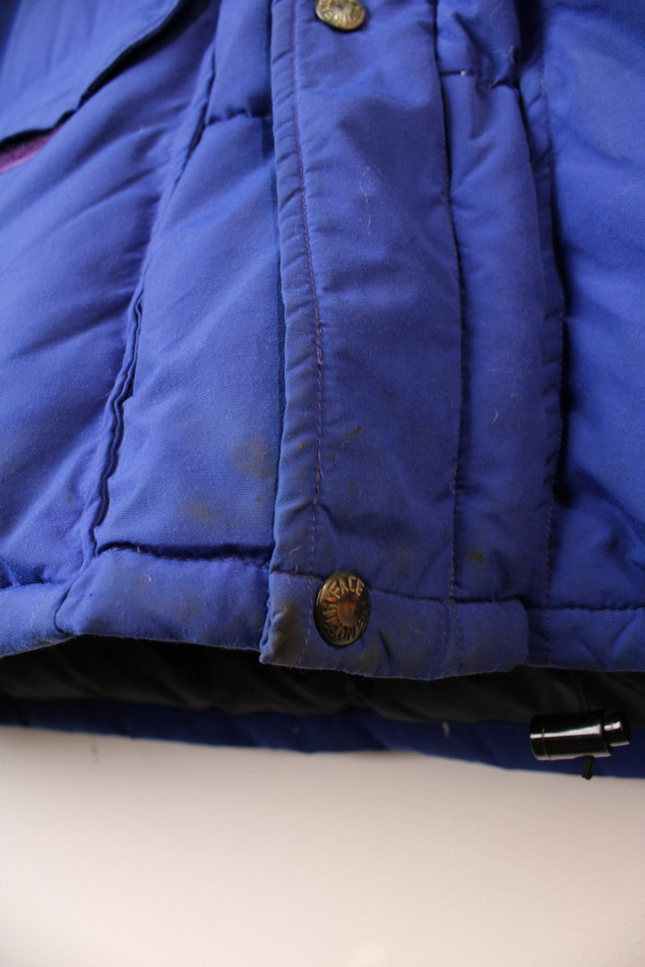 Vintage 90's The North Face Baltoro Down Puffer Coat in a blue colourway, zip up with side pockets, insulated, has a detachable hood and the logo embroidered on the left sleeve. 