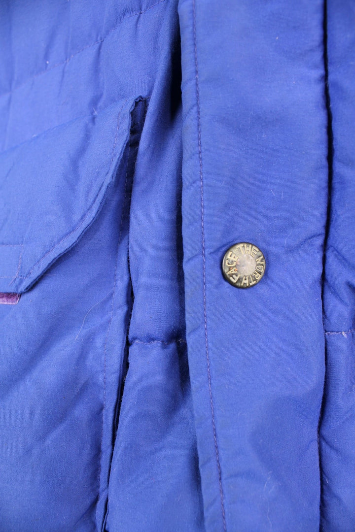 Vintage 90's The North Face Baltoro Down Puffer Coat in a blue colourway, zip up with side pockets, insulated, has a detachable hood and the logo embroidered on the left sleeve. 