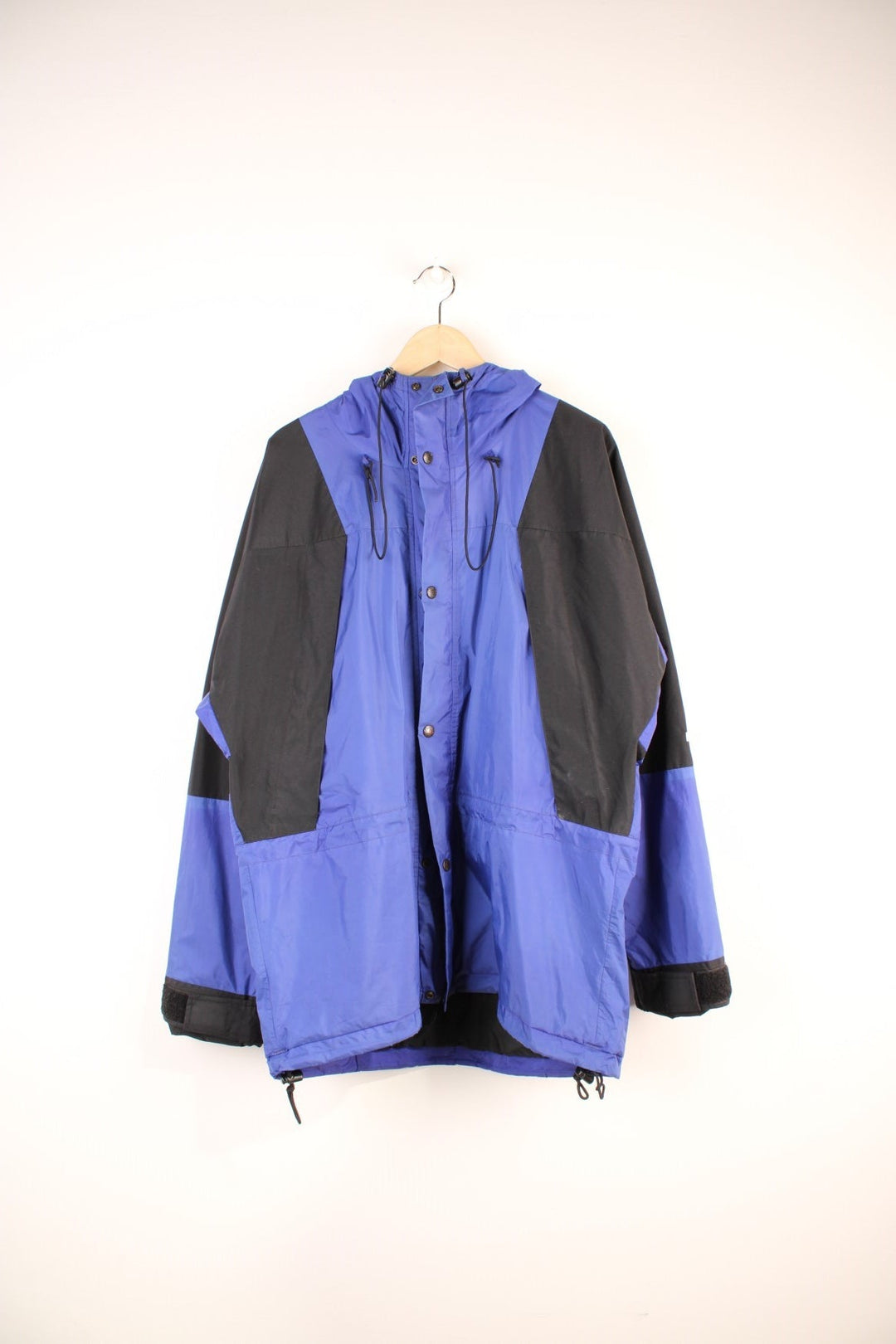 The North Face Mountain Light Gore-Tex Jacket in a blue and black colourway, zip up with side pockets, hooded, has a mesh lining, and the logo embroidered on the left sleeve. 