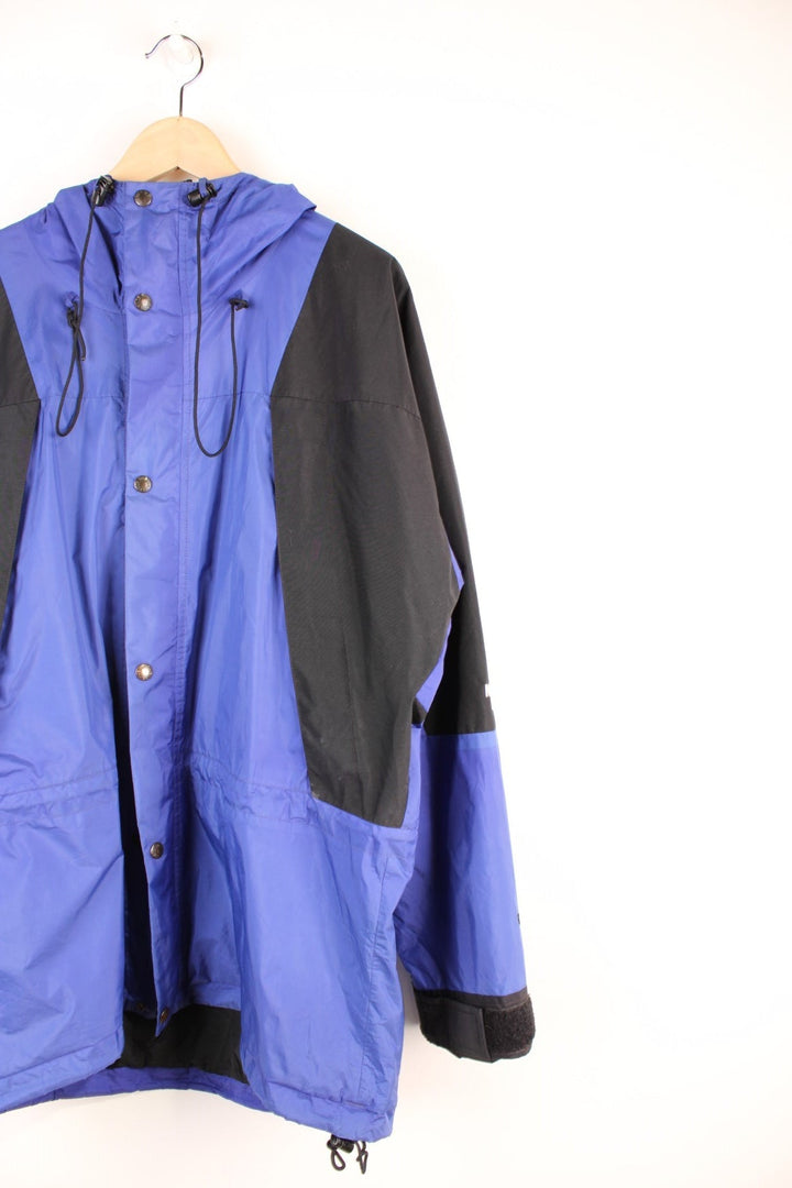 The North Face Mountain Light Gore-Tex Jacket in a blue and black colourway, zip up with side pockets, hooded, has a mesh lining, and the logo embroidered on the left sleeve. 