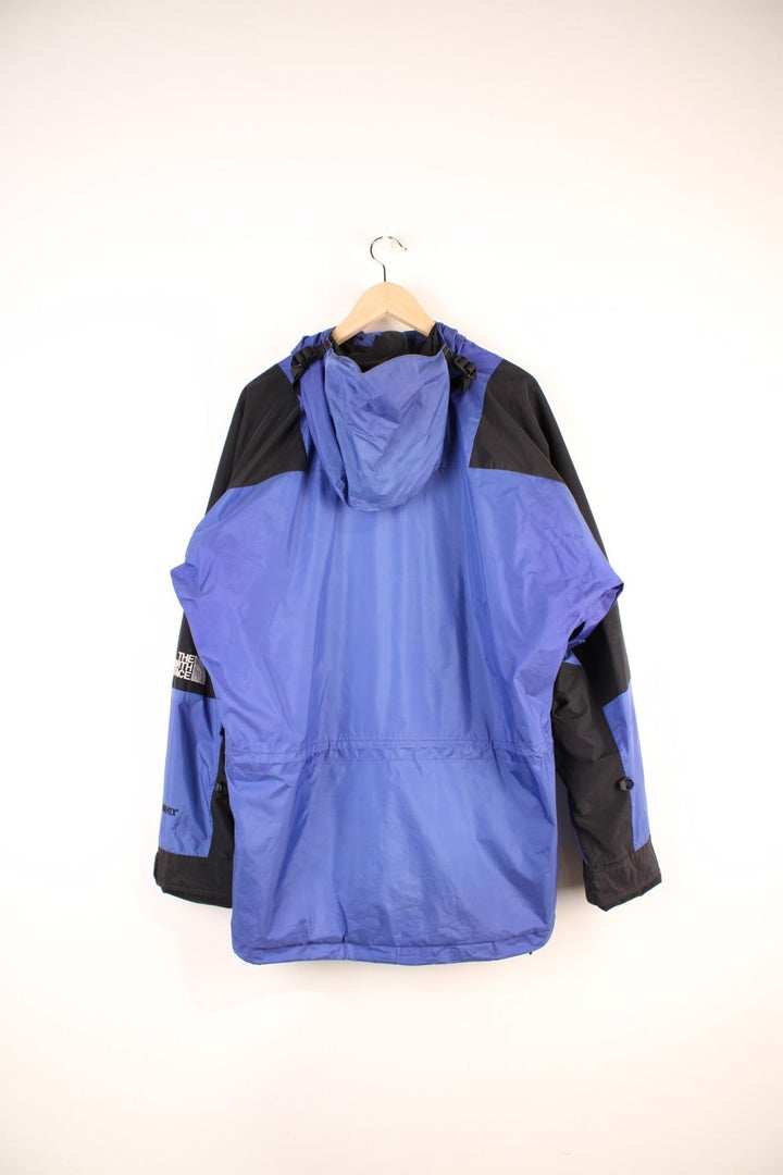 The North Face Mountain Light Gore-Tex Jacket in a blue and black colourway, zip up with side pockets, hooded, has a mesh lining, and the logo embroidered on the left sleeve. 