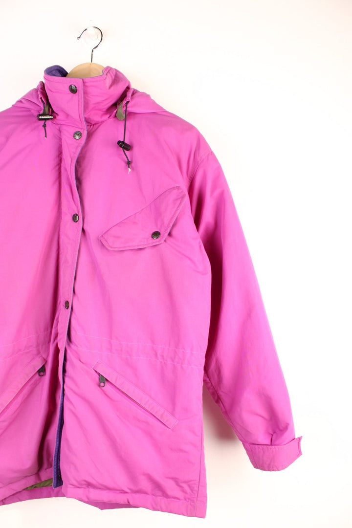 The North Face Down Parka Coat in a pink colourway, zip and button up, has a detachable hood, multiple pockets, insulated, and has the logo embroidered on the left sleeve. 