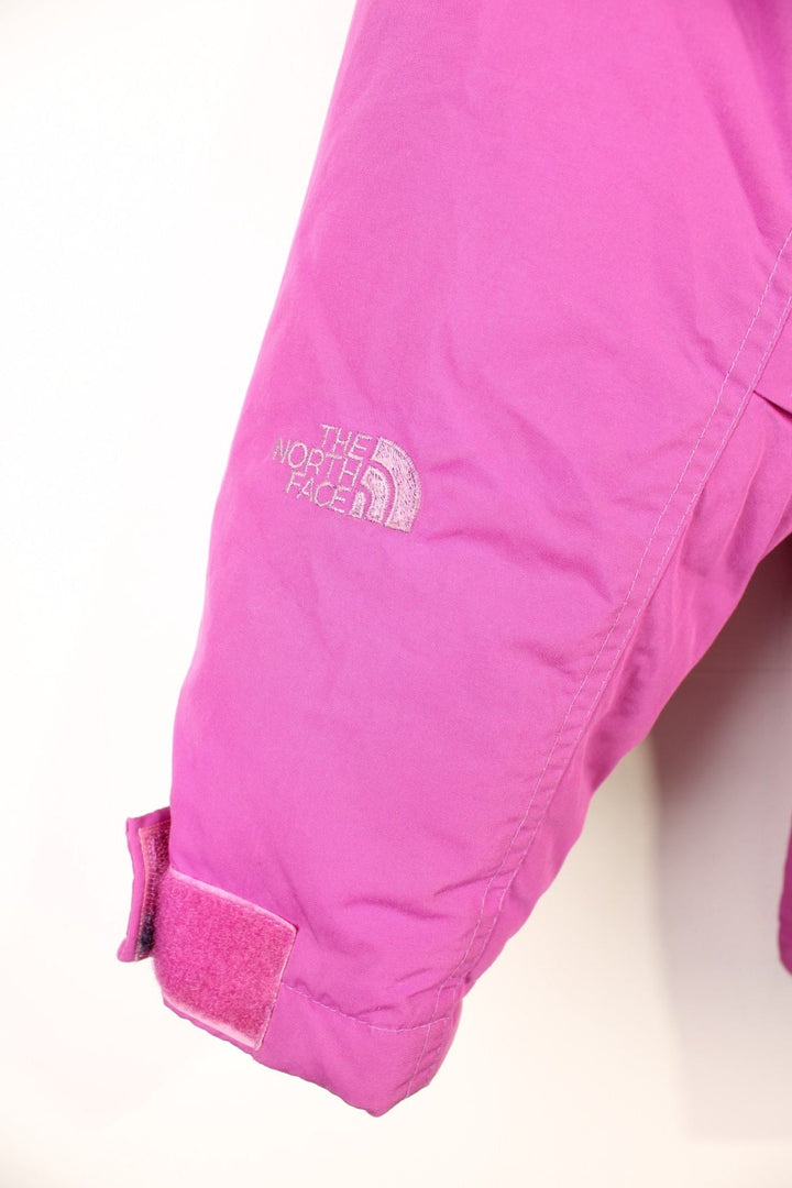 The North Face Down Parka Coat in a pink colourway, zip and button up, has a detachable hood, multiple pockets, insulated, and has the logo embroidered on the left sleeve. 