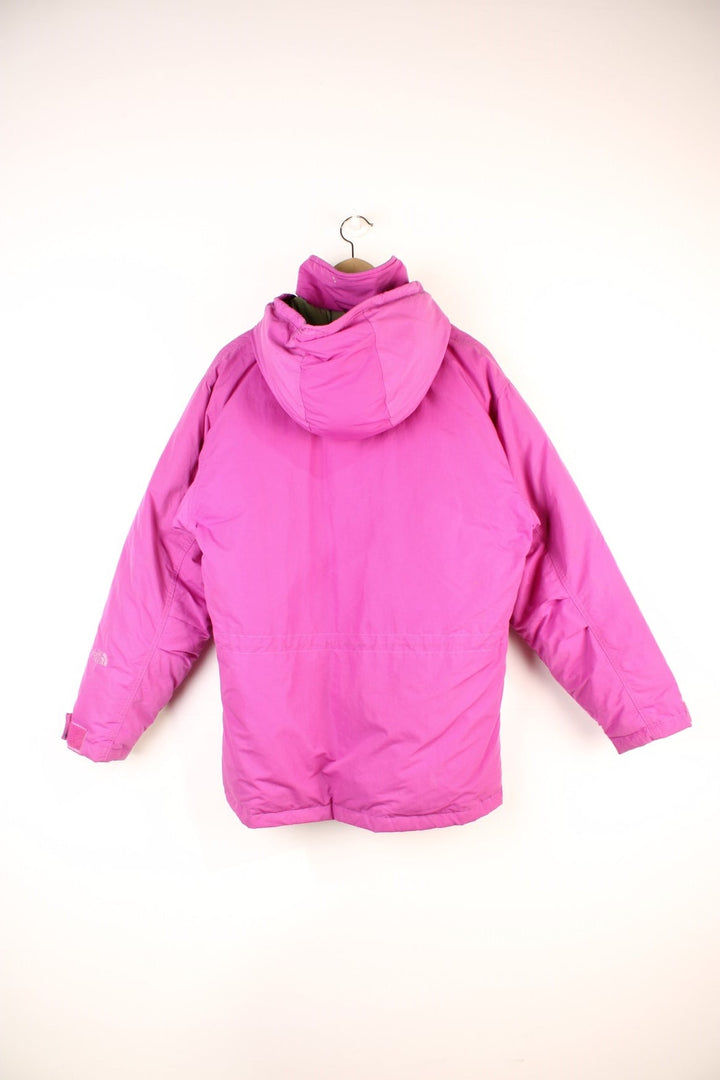 The North Face Down Parka Coat in a pink colourway, zip and button up, has a detachable hood, multiple pockets, insulated, and has the logo embroidered on the left sleeve. 