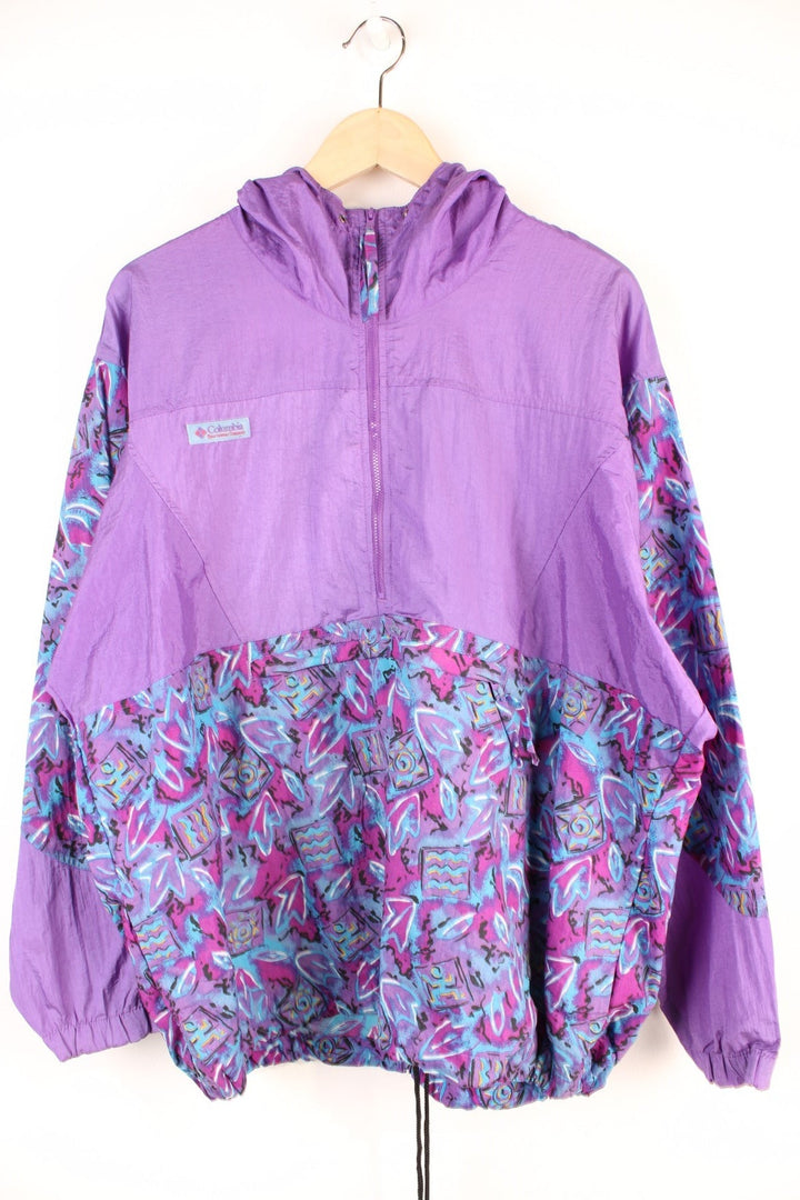 90's Columbia Patterned Windbreaker in a purple and blue colourway, surf style sportswear, half zip with pouch pockets, has adjustable waist line toggles, hooded and has the logo embroidered on the front. 