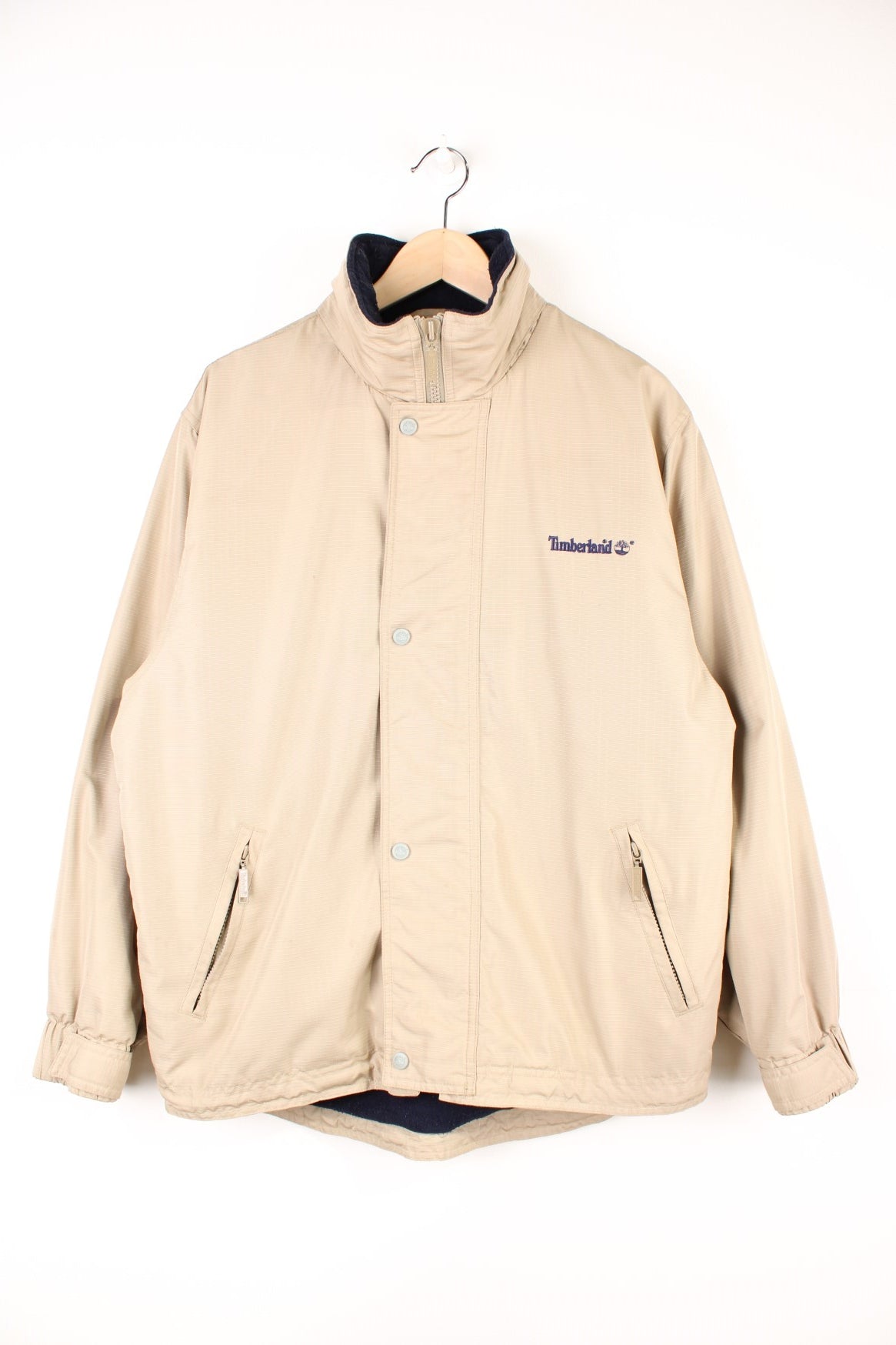 Timberland Jacket in a tanned colourway, zip and button up, side pockets, has a hideable hood, insulated with a fleece lining, and has the logo embroidered on the front and back. 