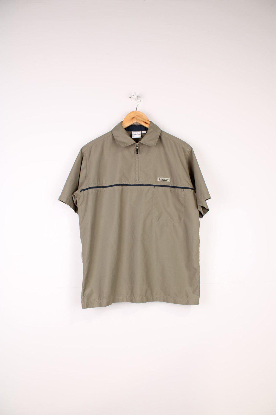 Ellesse Casual Shirt in a tanned brown colourway with a navy blue stripe going across the front, quarter zip up and has a chest pocket with the logo embroidered above it.