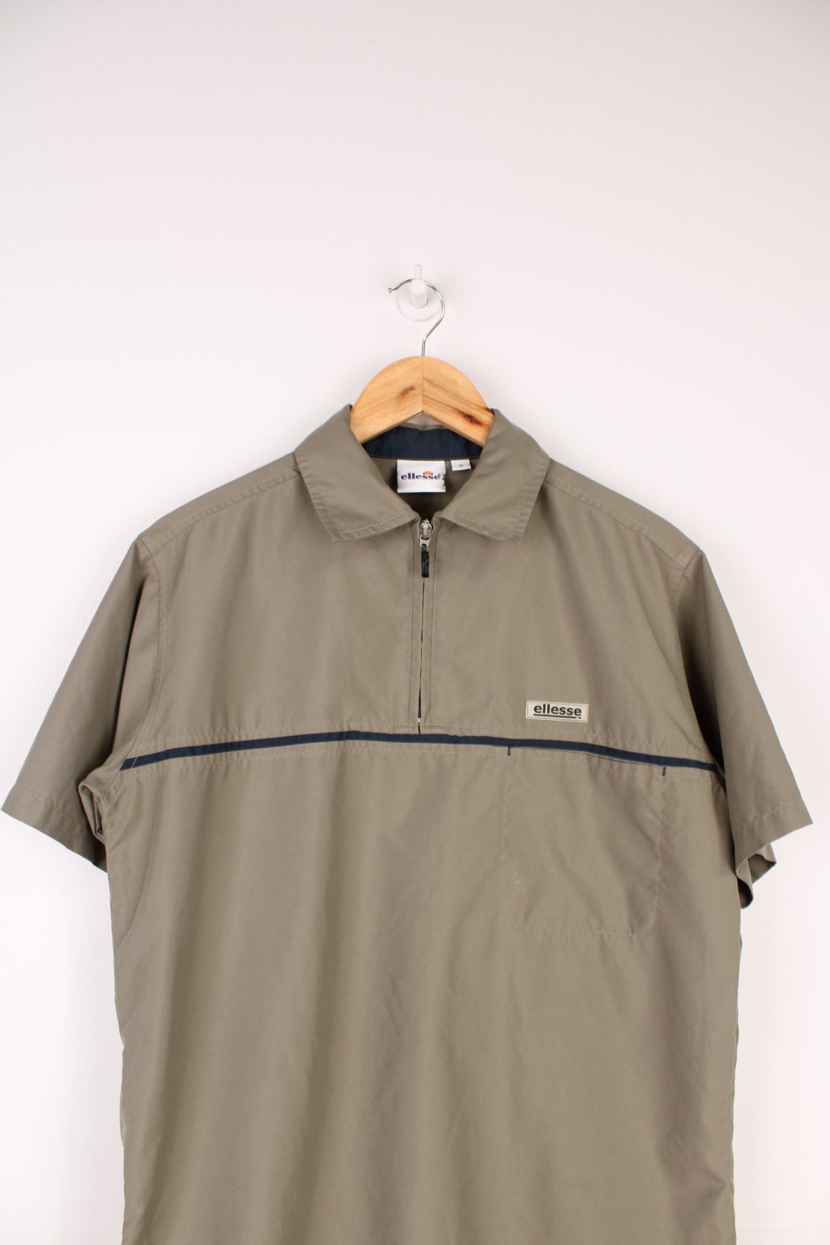 Ellesse Casual Shirt in a tanned brown colourway with a navy blue stripe going across the front, quarter zip up and has a chest pocket with the logo embroidered above it.