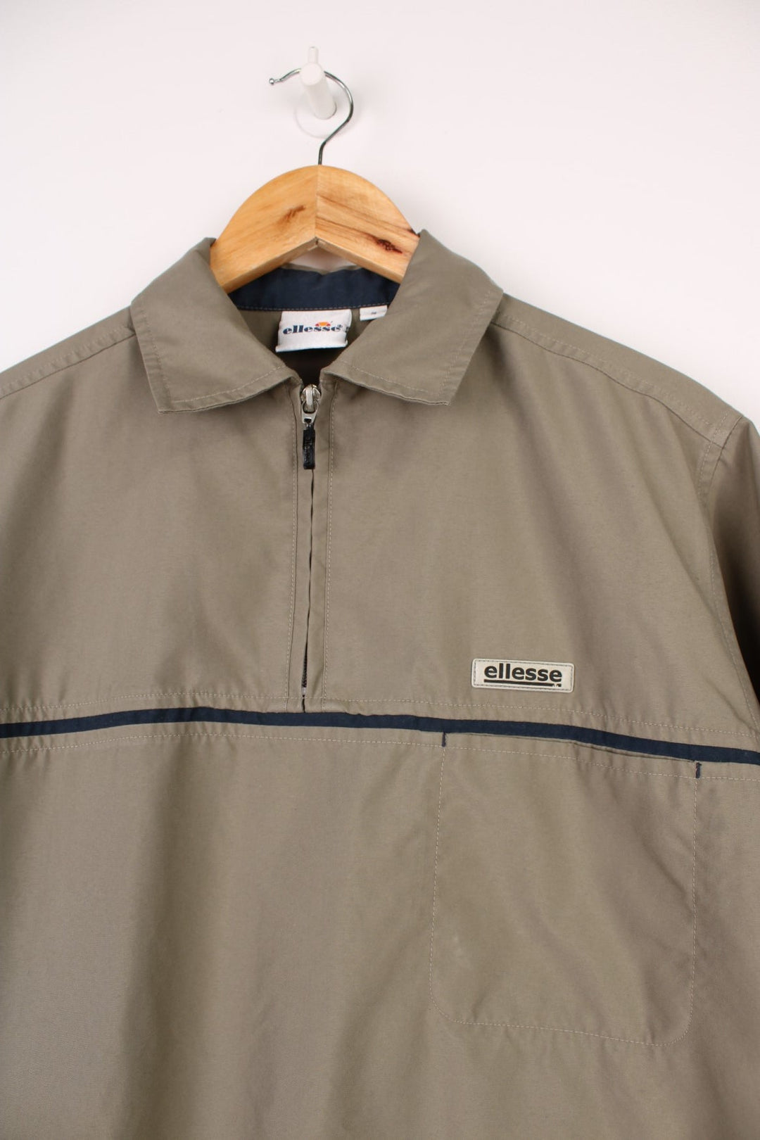 Ellesse Casual Shirt in a tanned brown colourway with a navy blue stripe going across the front, quarter zip up and has a chest pocket with the logo embroidered above it.