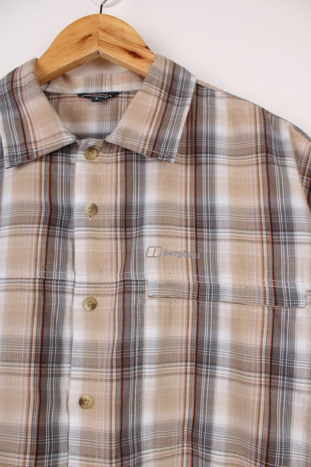 Berghaus Odyssey Shirt in a tanned brown, black and orange plaid colourway, button up shirt which has a chest pocket with the logo embroidered on it.