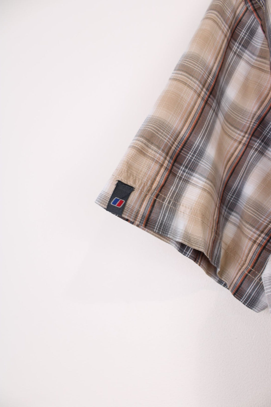 Berghaus Odyssey Shirt in a tanned brown, black and orange plaid colourway, button up shirt which has a chest pocket with the logo embroidered on it.