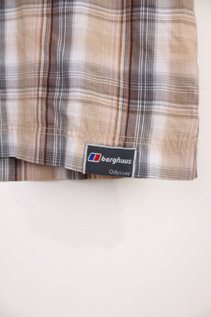 Berghaus Odyssey Shirt in a tanned brown, black and orange plaid colourway, button up shirt which has a chest pocket with the logo embroidered on it.