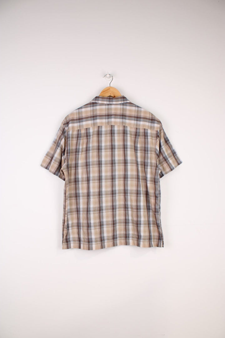 Berghaus Odyssey Shirt in a tanned brown, black and orange plaid colourway, button up shirt which has a chest pocket with the logo embroidered on it.