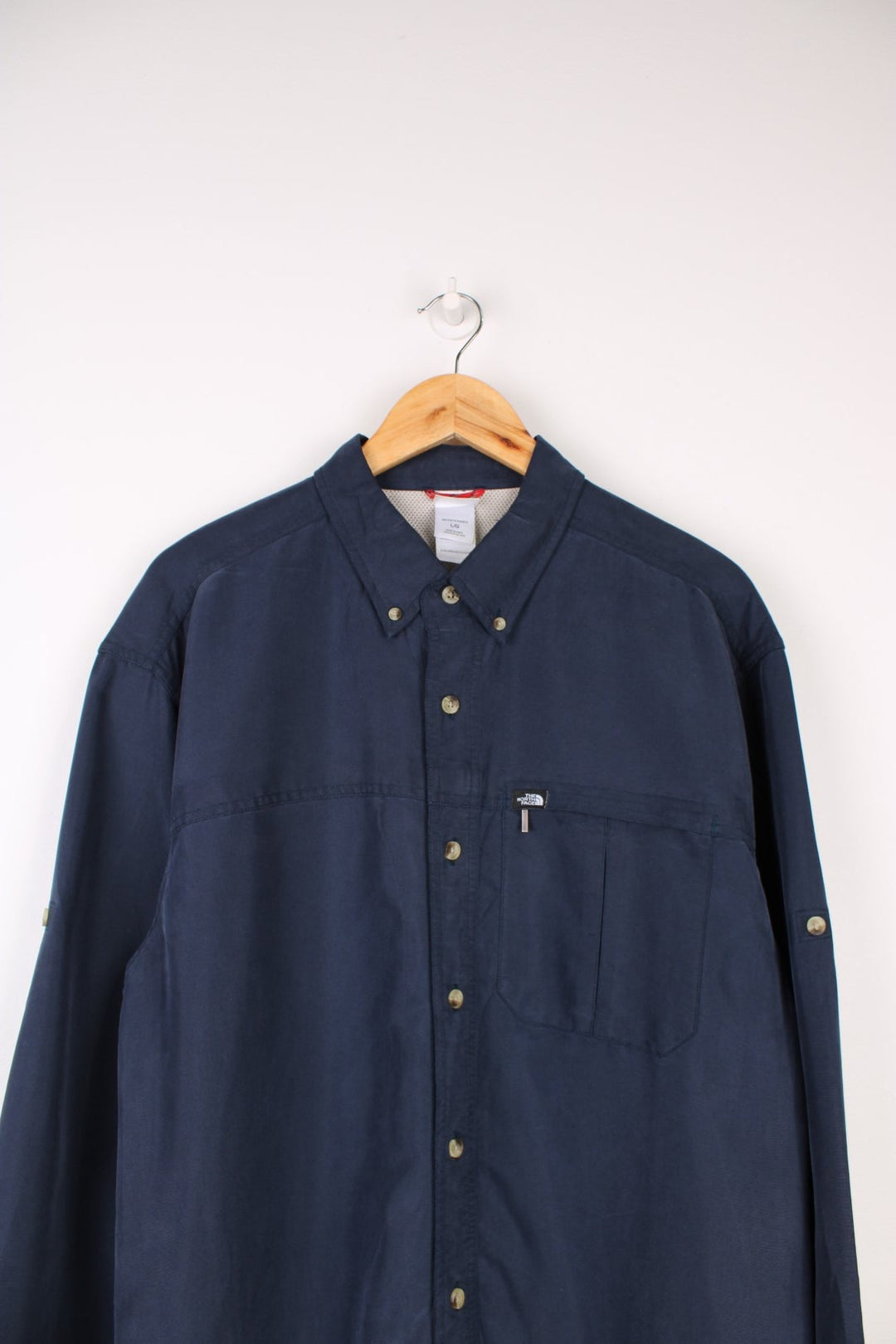 The North Face Long Sleeved Shirt in a navy blue colourway, button up and has a chest pocket with the logo embroidered on it.