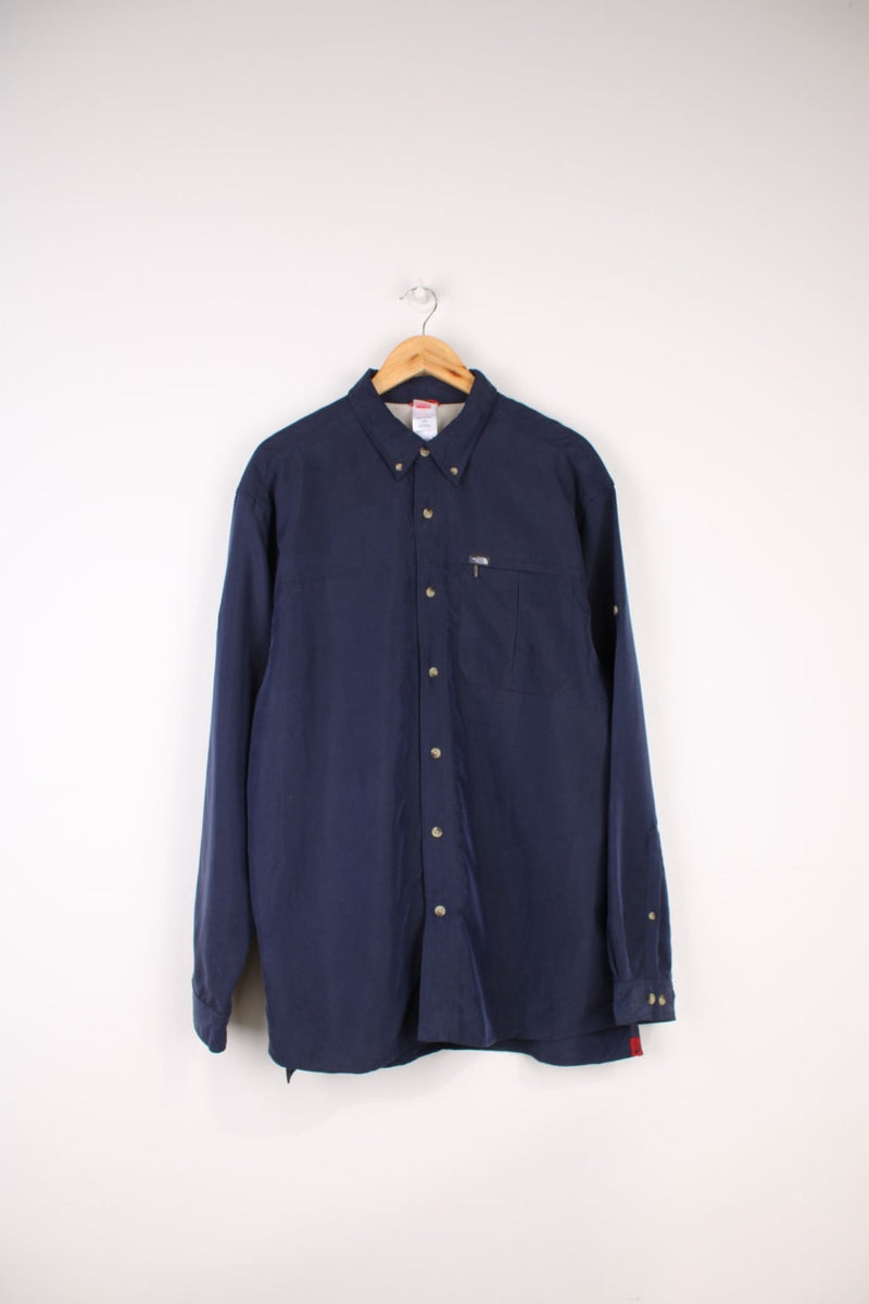 The North Face Long Sleeved Shirt in a navy blue colourway, button up and has a chest pocket with the logo embroidered on it.