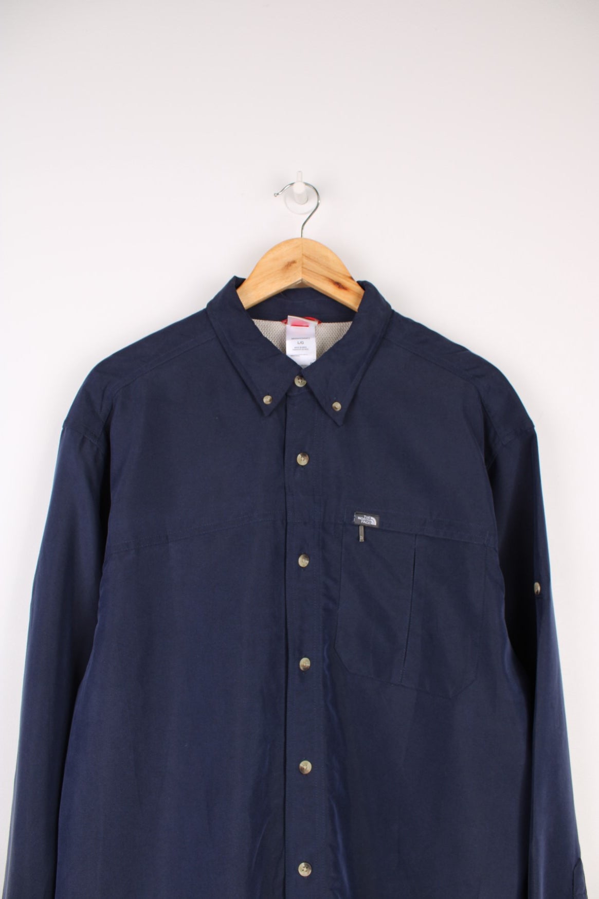 The North Face Long Sleeved Shirt in a navy blue colourway, button up and has a chest pocket with the logo embroidered on it.