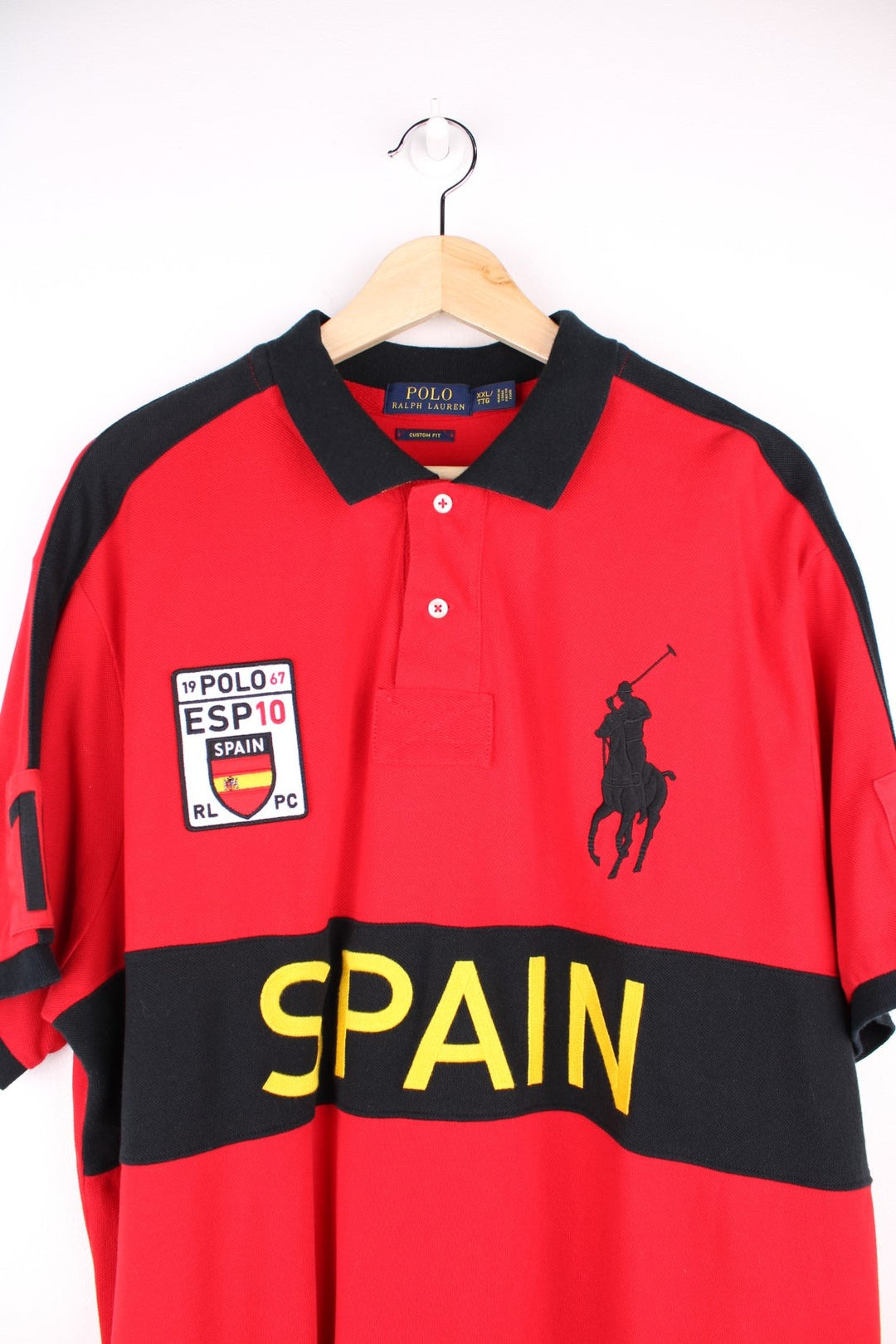 Ralph Lauren Spain polo shirt in a red colourway with black detail. Ralph Lauren logo and Spain graphic printed on front.