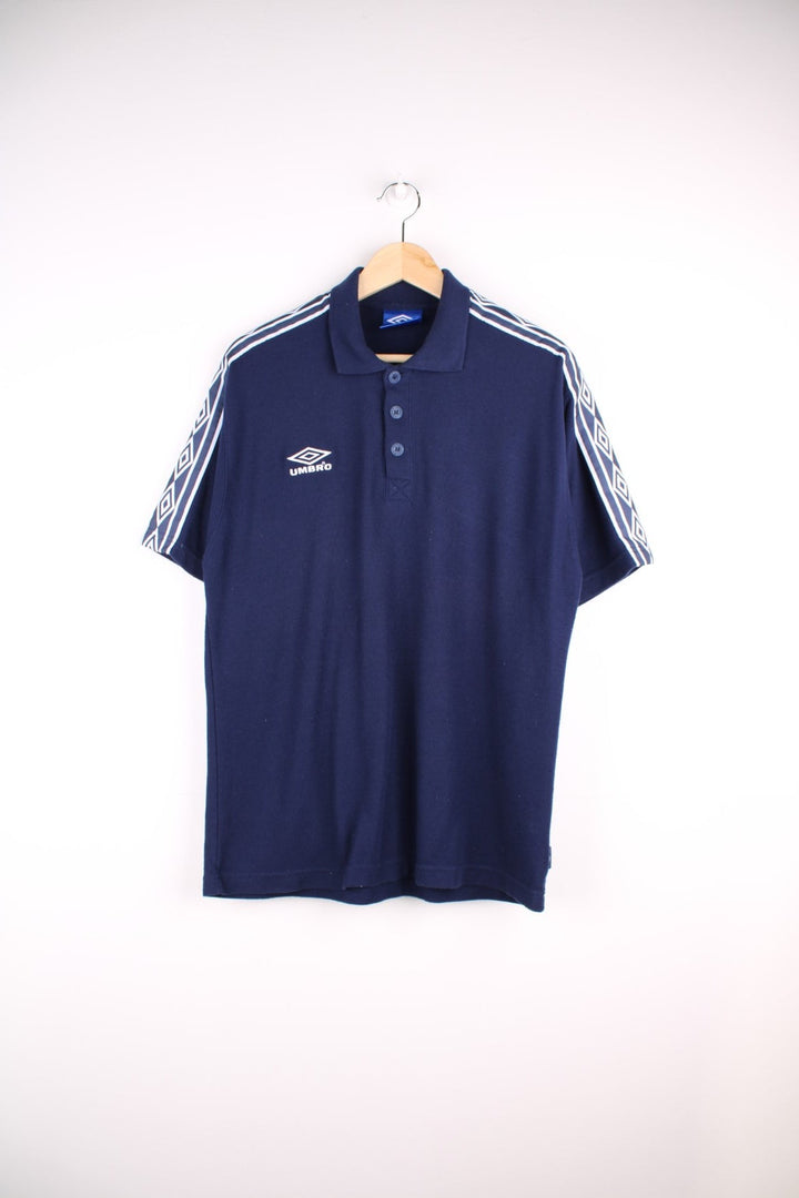 Umbro polo shirt in a navy colourway with the logo embroidered on the front and white sleeve detail.