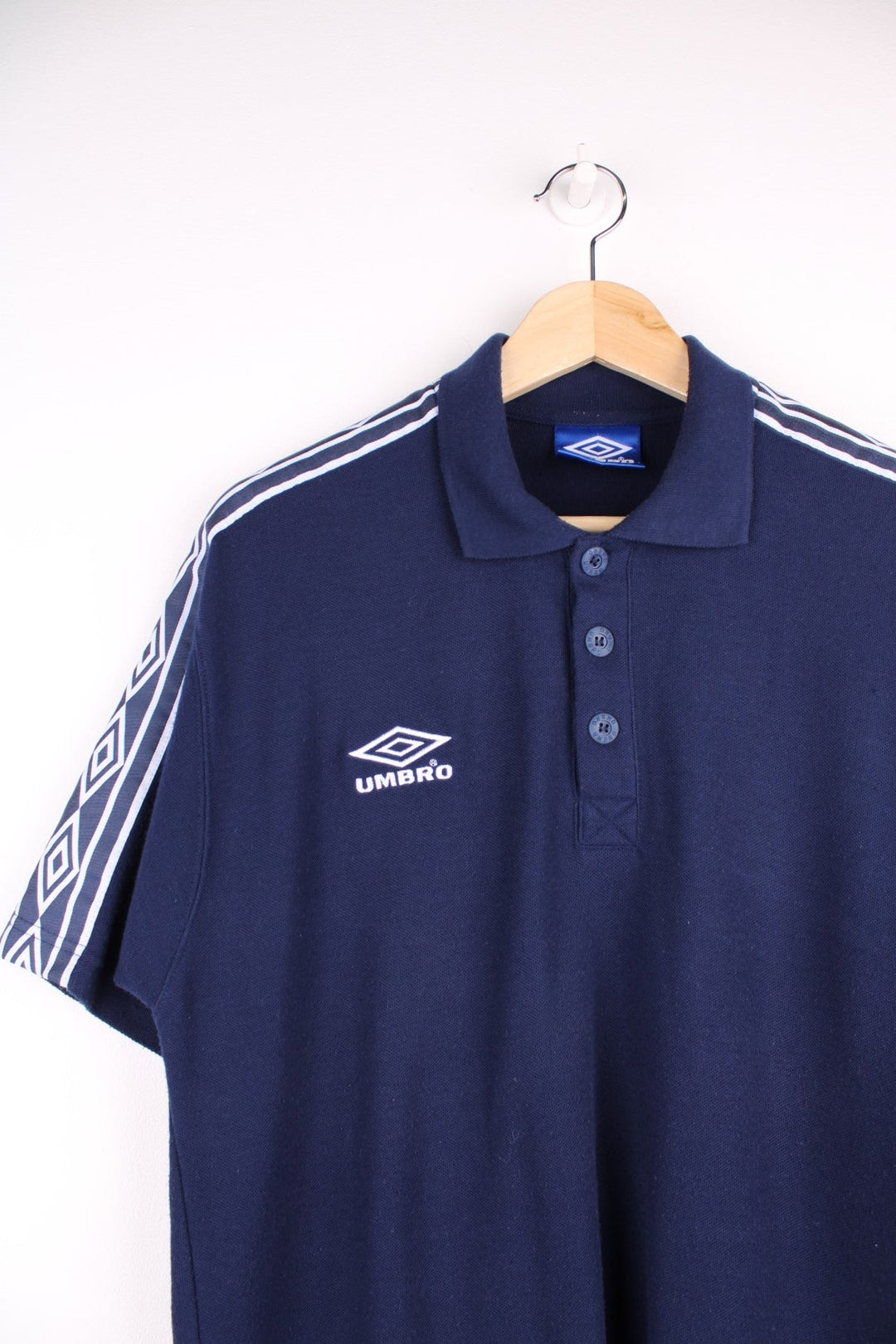 Umbro polo shirt in a navy colourway with the logo embroidered on the front and white sleeve detail.