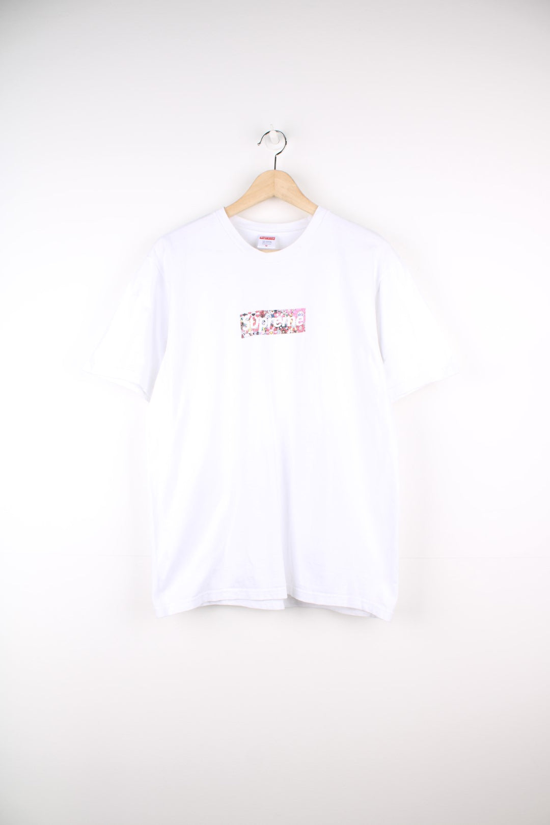 Supreme Murakami Relief Box Logo T-Shirt in a white colourway, has the supreme box logo with a floral emoji print going around, and also has 'Covid 19 Relief Fund 2020' printed on the back.