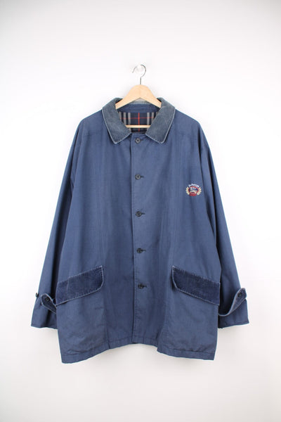 Vintage Burberry Sport Mac Coat in a blue colourway with a corduroy collar, button up with side pockets, and has the logo embroidered on the front. 
