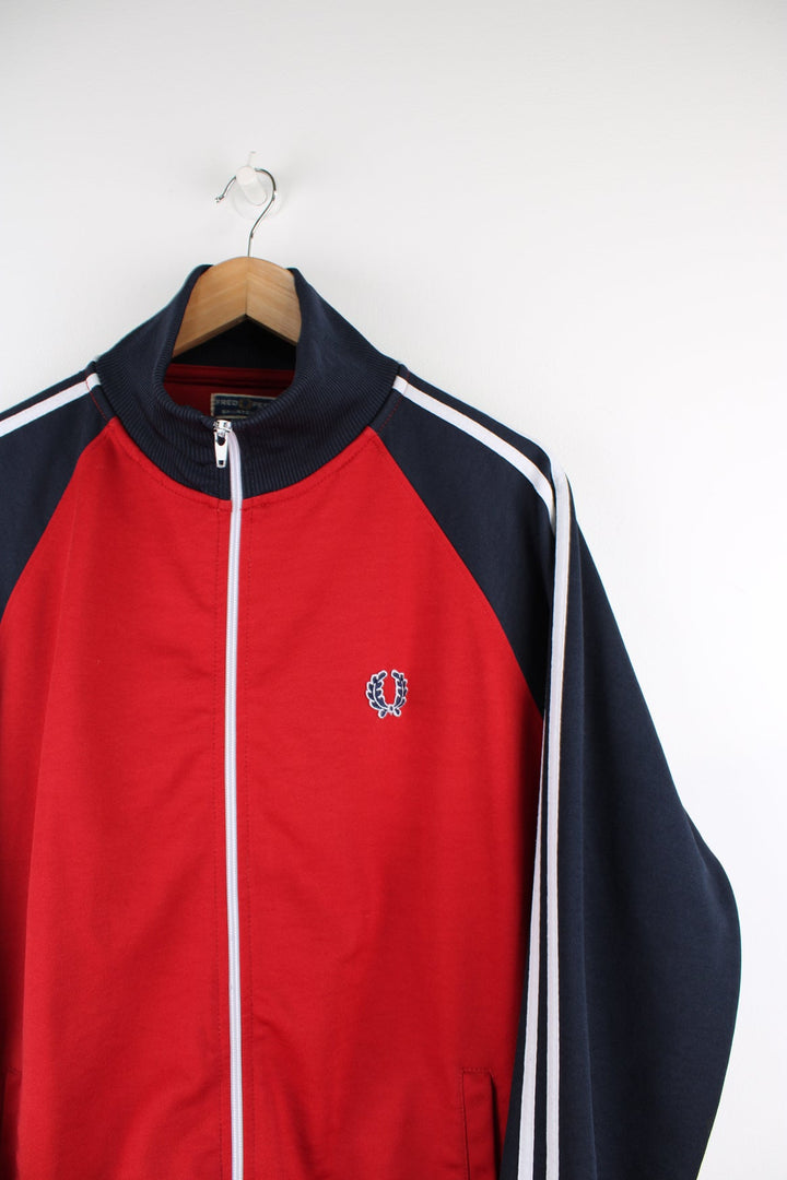 Fred Perry red and navy zip through tracksuit jacket, features signature embroidered logo on the chest and white stripes down the sleeves