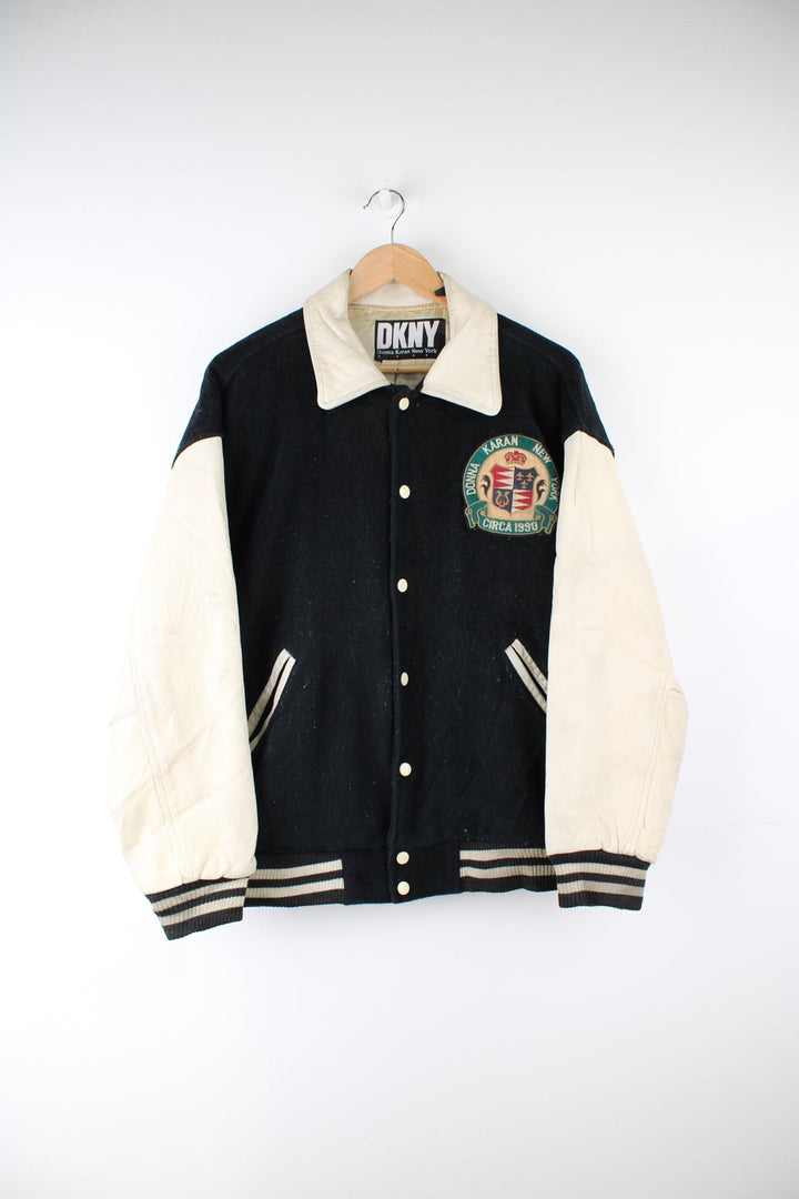 Vintage 90's DKNY black and white varsity jacket with wool body and leather sleeves, features embroidered badges and large spell-out motif on the back 