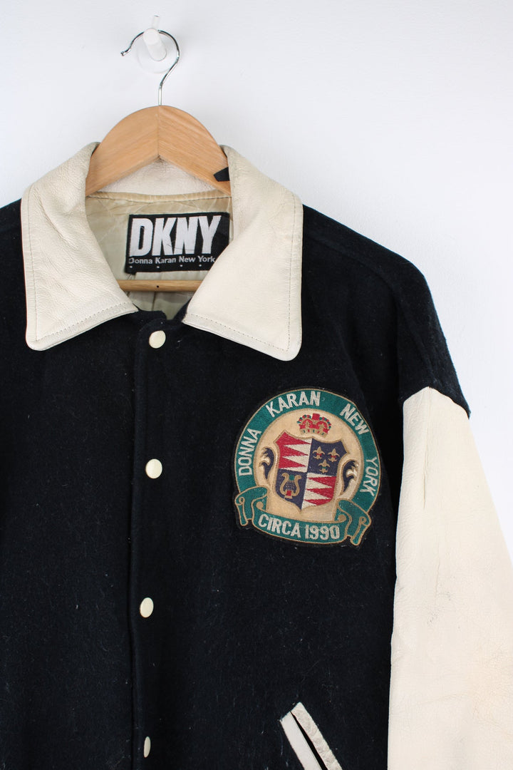 Vintage 90's DKNY black and white varsity jacket with wool body and leather sleeves, features embroidered badges and large spell-out motif on the back 