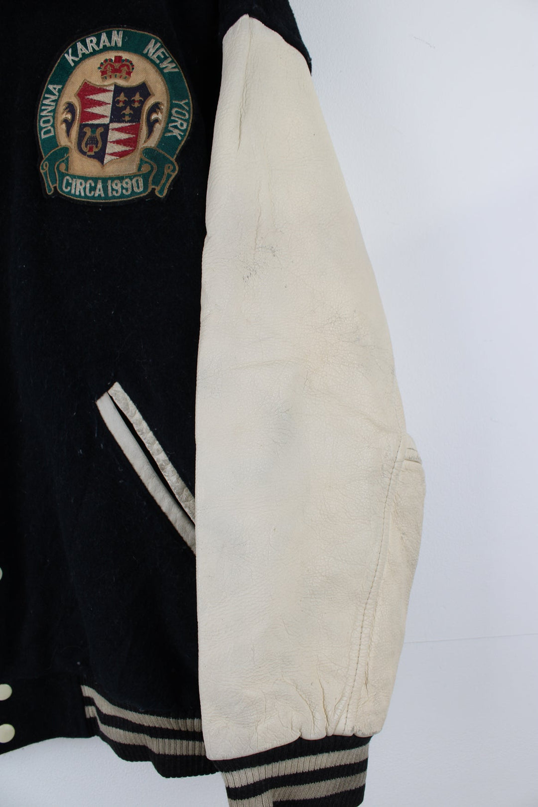 Vintage 90's DKNY black and white varsity jacket with wool body and leather sleeves, features embroidered badges and large spell-out motif on the back 