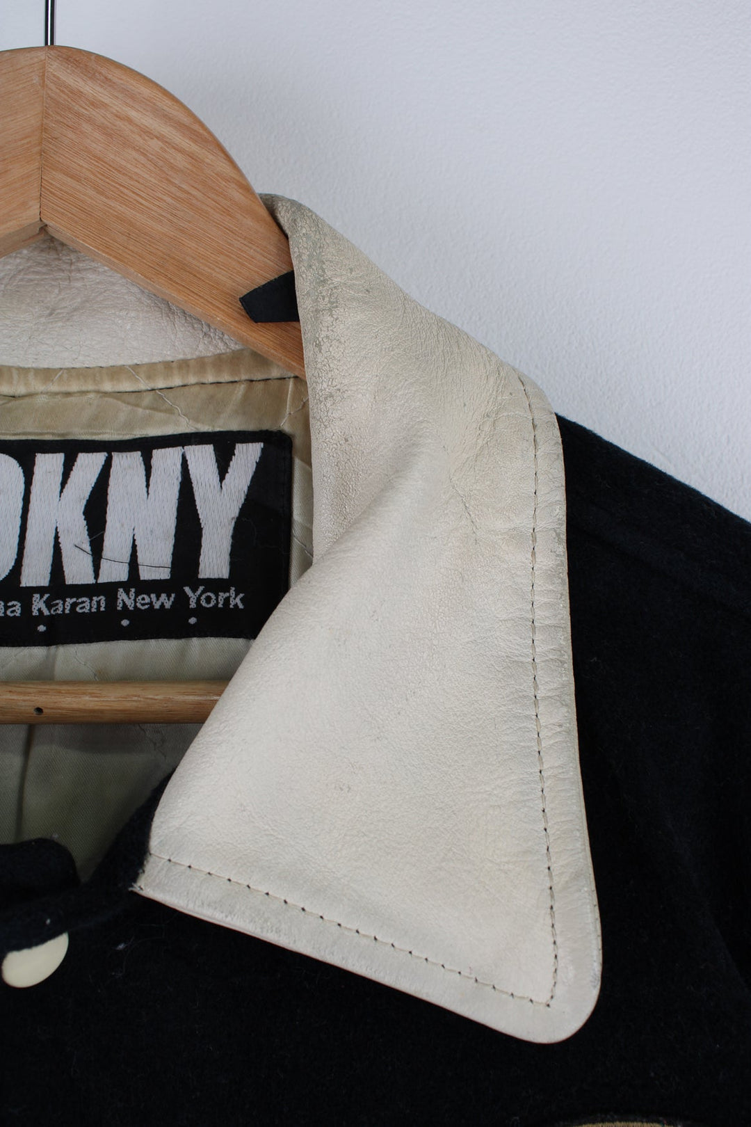 Vintage 90's DKNY black and white varsity jacket with wool body and leather sleeves, features embroidered badges and large spell-out motif on the back 