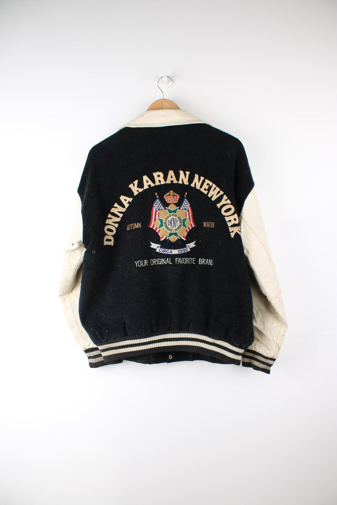 Vintage 90's DKNY black and white varsity jacket with wool body and leather sleeves, features embroidered badges and large spell-out motif on the back 