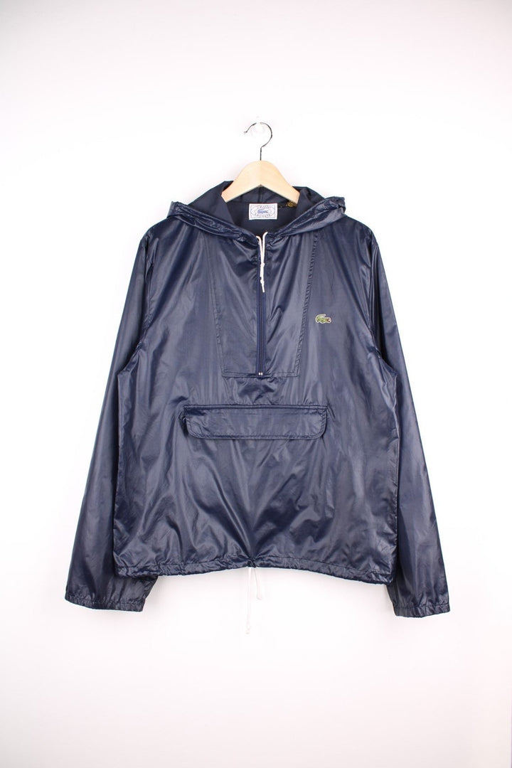 Vintage Izod Lacoste Pullover Windbreaker in a blue colourway, half zip up and has a pouch pocket, hooded and the logo is embroidered on the front. 